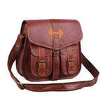 Reddish-brown crossbody satchel with two buckle pockets and a shoulder strap, three-quarter view.