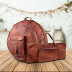 Brown round cymbal case and matching rectangular drumstick bag displayed together on a wooden surface.
